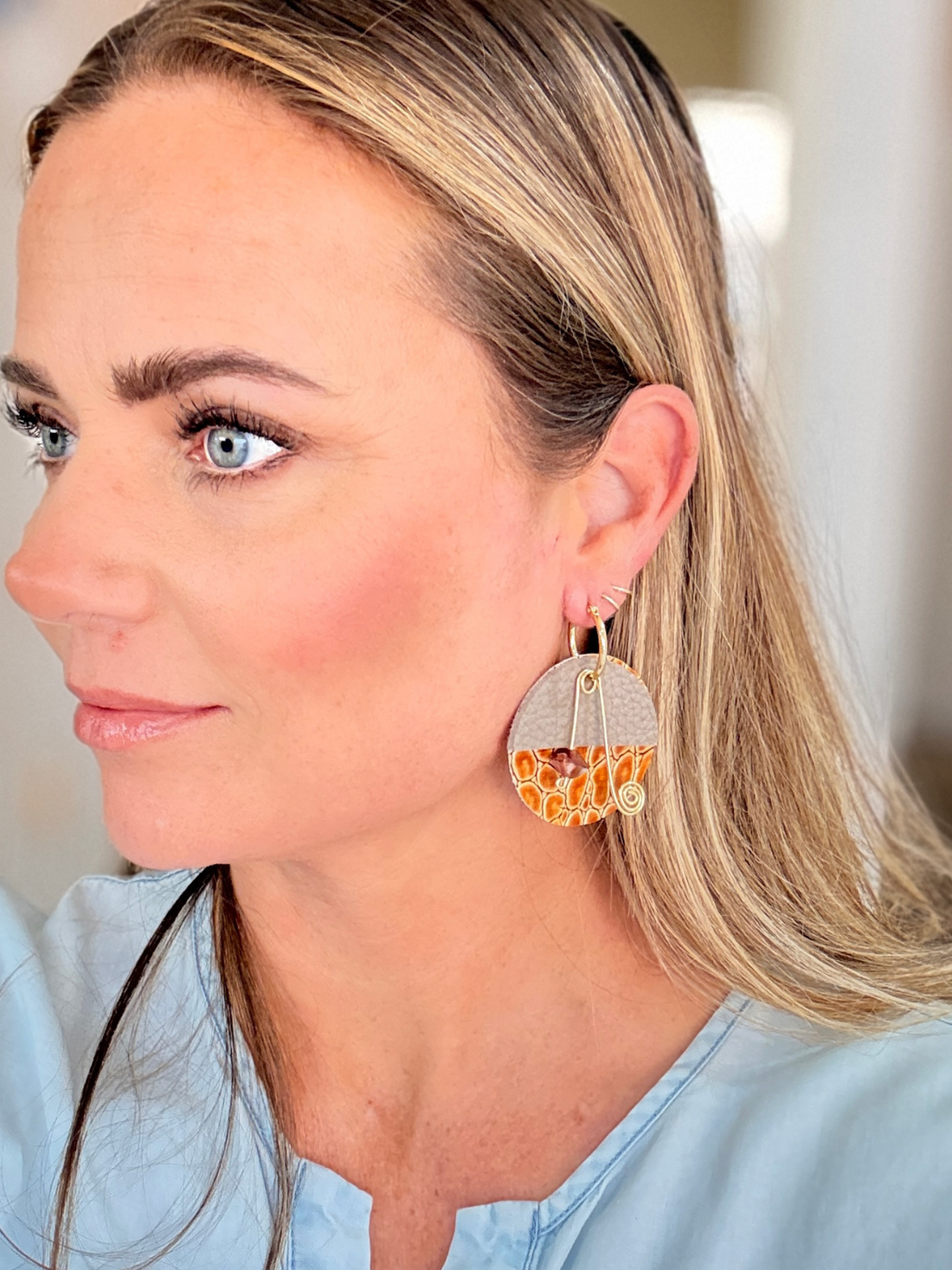 Woman wearing large earrings with a neutral background
